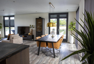 Moderne woon- en eetruimte in de Water Cube-lodge bij vakantiepark BreeBronne, Nederland, met uitzicht op het meer.