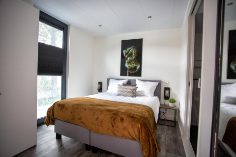 Moderne slaapkamer bij Water Cube lodge in BreeBronne, Nederland, met tweepersoonsbed en muurkunst.