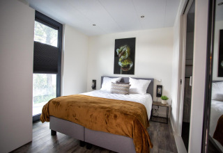 Moderne slaapkamer bij Water Cube lodge in BreeBronne, Nederland, met tweepersoonsbed en muurkunst.
