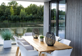 Moderne terras aan het meer bij Water Cube-lodge in Holiday Park BreeBronne, Nederland, met tafel en stoelen.