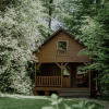 Wooden cabin surrounded by lush green trees at Waldbad Isny - Glampingaccommodaties Baden-Württemberg, Germany.