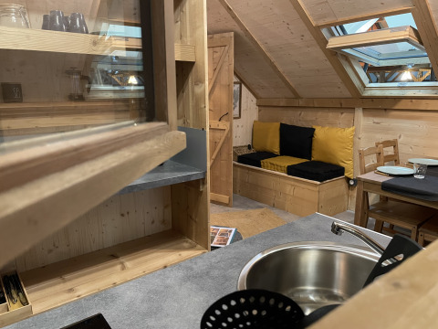 Vue intérieure de la Safari Lodge «All Season» au Chianti Glamping Resort avec décor en bois et canapé.