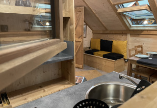 Vue intérieure de la Safari Lodge «All Season» au Chianti Glamping Resort avec décor en bois et canapé.