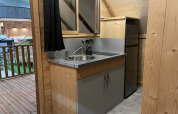 Petite kitchenette avec évier, plaque de cuisson et réfrigérateur dans une tente safari au Chianti Glamping Resort.