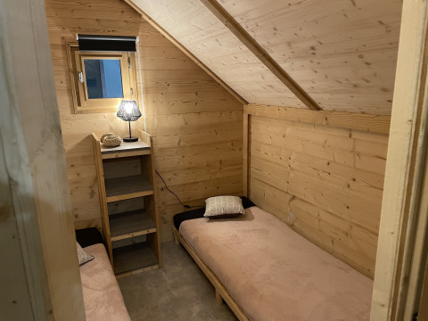 Intérieur en bois avec deux lits simples à la Safari Lodge «All Season» au Chianti Glamping Resort en Italie.