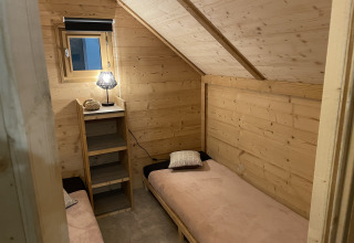 Intérieur en bois avec deux lits simples à la Safari Lodge «All Season» au Chianti Glamping Resort en Italie.