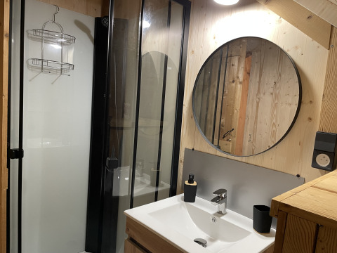 Salle de bain moderne avec miroir rond et douche à la Safari Lodge « All Season » au Chianti Glamping Resort, Italie.