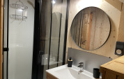 Salle de bain moderne avec miroir rond et douche à la Safari Lodge « All Season » au Chianti Glamping Resort, Italie.