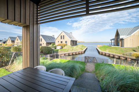 Vista da un patio coperto sull’acqua e sulle ville in legno presso Villa Oesterdam, Oesterdam Resort, Paesi Bassi.