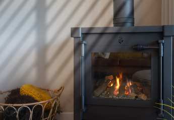 Moderner Kamin mit Flammen in der Villa «Oesterdam» im Oesterdam Resort, Niederlande, und Korb daneben.