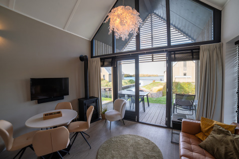 Lodge moderno con ampie finestre, arredamento elegante e vista sul lago presso Villa Oesterdam, Oesterdam Resort, Paesi Bassi.