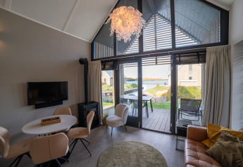 Moderne Lodge mit großen Fenstern, stilvollem Interieur und Seeblick, Villa Oesterdam, Oesterdam Resort, Niederlande.