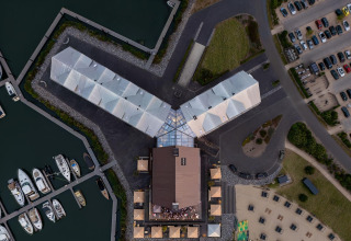 Vista aerea della sistemazione glamping Villa Oesterdam con edifici collegati e marina.
