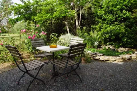 Gemütlicher Gartenbereich mit vier Holzstühlen und Tisch im Grünen im Domaine EcÔtelia, Nouvelle-Aquitaine, Frankreich.