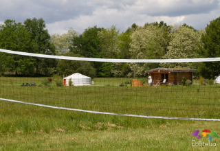 Vista su una rete da pallavolo, una yurta e una casetta di legno a Domaine EcÔtelia in Nouvelle-Aquitaine, Francia.