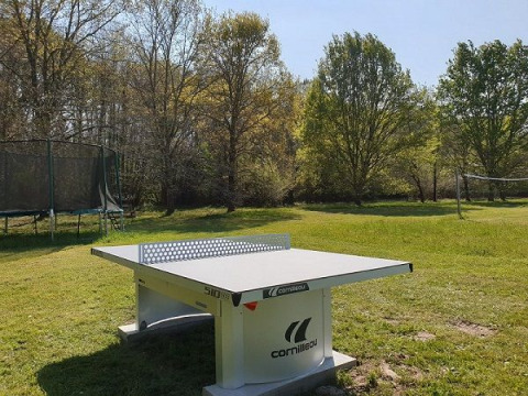 Udendørs bordtennisbord, trampolin og volleyballnet på en grøn græsplæne i Domaine EcÔtelia, Nouvelle-Aquitaine.