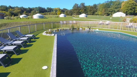 Natuurlijke zwemvijver met ligstoelen en yurts bij vakantiepark Domaine EcÔtelia in Nouvelle-Aquitaine, Frankrijk