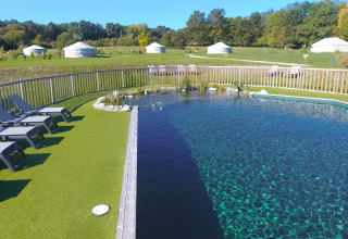 Naturpool mit Liegestühlen und Blick auf Jurten im Domaine EcÔtelia Ferienpark, Nouvelle-Aquitaine, Frankreich