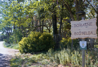 Cartello d’ingresso al parco vacanze Domaine EcÔtelia in Nouvelle-Aquitaine, Francia, immerso nel verde bosco.