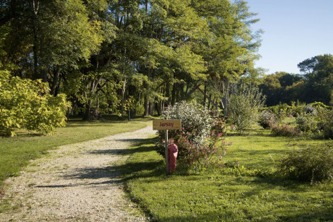 Grindpad met 'Jersey'-bord in Domaine EcÔtelia vakantiepark, omgeven door groene bomen en struiken.