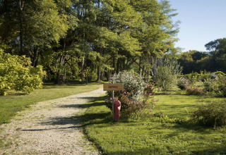 Allée de gravier et panneau 'Jersey' au Domaine EcÔtelia, entouré d’arbres verts et d’arbustes dans le parc.