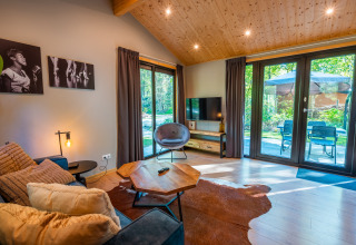 Modern lodge living room at Velthorst, De Wiltzangh, Netherlands, with large windows to a sunny terrace.