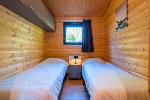 Gemütliches Schlafzimmer mit zwei Einzelbetten, Holzverkleidung und Fenster in der Velthorst-Lodge, De Wiltzangh.