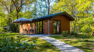 Velthorst Hot Tub Lodge i en grøn skov med udendørs siddeplads og have under klare forårsdage.