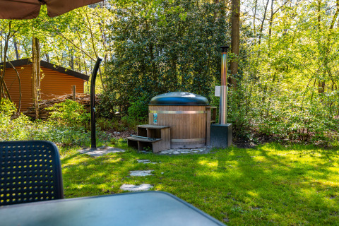 Outdoor hot tub surrounded by greenery at Velthorst lodge in Holiday park De Wiltzangh, Netherlands.