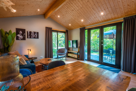 Bright living room in a Velthorst lodge at Holiday park De Wiltzangh, Netherlands, with large windows.