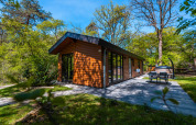 Wellness Lodge «Wood XL» en el parque vacacional De Wiltzangh, Países Bajos, rodeado de naturaleza verde.