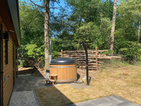 Jacuzzi exterior en Wellness Lodge «Wood XL» en el parque De Wiltzangh, Países Bajos, rodeado de naturaleza.