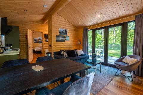 Acogedora sala en Wellness Lodge «Wood XL» con paredes de madera y vista al bosque en De Wiltzangh.