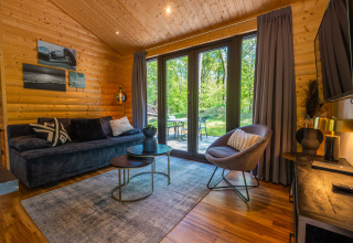 Woonruimte in Wellness Lodge «Wood XL» van Holiday park De Wiltzangh met zithoek en zicht op tuin.