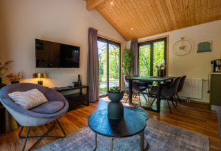 Salon moderne et coin repas dans la Wellness Lodge « Wood XL » au parc De Wiltzangh avec vue sur la nature.