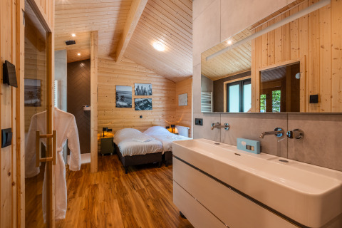 Intérieur du Wellness Lodge «Wood XL» au Holiday park De Wiltzangh, avec deux lits simples et murs en bois.