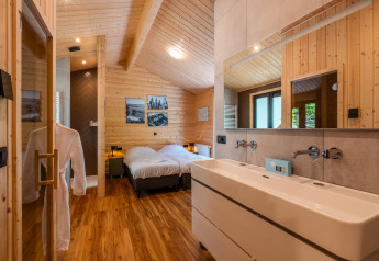 Innenraum der Wellness Lodge «Wood XL» im Ferienpark De Wiltzangh mit Doppelbett und Holzwänden.