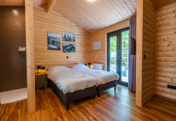 Bedroom at Wellness Lodge «Wood XL» featuring wooden interior, twin beds, and terrace view, Holiday park De Wiltzangh.