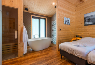 Wellness lodge interior featuring a freestanding bathtub, sauna, and wood-paneled walls at De Wiltzangh.
