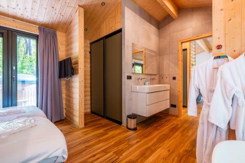 Moderne Wellness Lodge «Wood XL» bij Holiday park De Wiltzangh in Nederland, met houten interieur en slaapkamer.