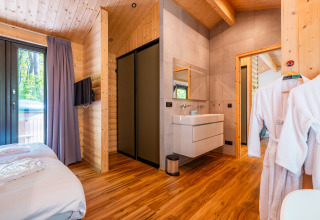 Moderno Wellness Lodge «Wood XL» en Holiday park De Wiltzangh, Países Bajos, con decoración de madera y dormitorio.