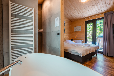 Modern Wellness Lodge ‘Wood XL’ with bathtub and bedroom inside Holiday park De Wiltzangh in the Netherlands.