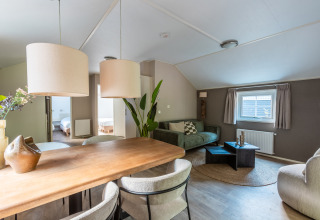 Lichte, moderne woonkamer in tiny house Heidelodge op vakantiepark De Wiltzangh, Nederland, met eet- en zithoek.