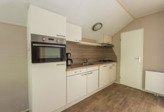 Modern kitchenette at Heidelodge, Holiday park De Wiltzangh, Netherlands, with oven, sink, and gas stove.