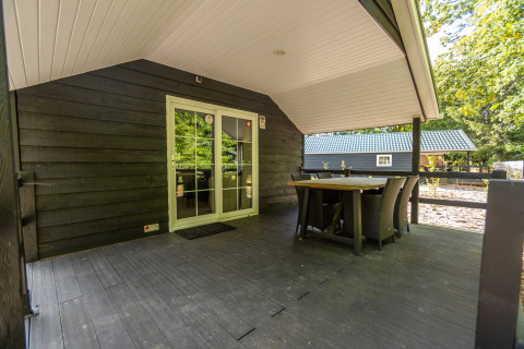 Terrasse couverte avec table à manger à la tiny house Heidelodge, Holiday park De Wiltzangh, Pays-Bas.