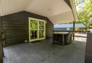 Overdækket terrasse med spisebord ved tiny house Heidelodge, Holiday park De Wiltzangh, Holland.