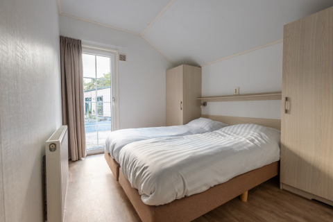 Chambre de la tiny house Heidelodge au parc de vacances De Wiltzangh, Pays-Bas, avec lit double et armoires.