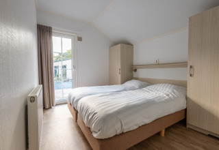 Camera da letto nella tiny house Heidelodge al parco vacanze De Wiltzangh, Paesi Bassi, con letto doppio e armadi.