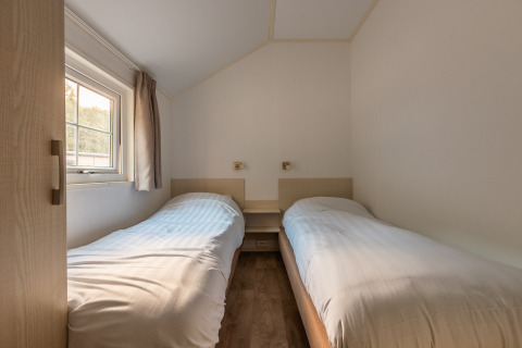 Kleine slaapkamer met twee eenpersoonsbedden in Heidelodge op Holiday park De Wiltzangh, Nederland, daglicht.