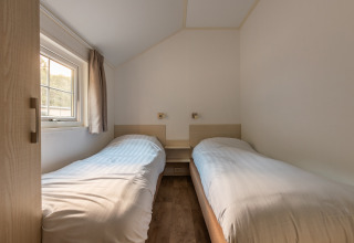 Kleine slaapkamer met twee eenpersoonsbedden in Heidelodge op Holiday park De Wiltzangh, Nederland, daglicht.